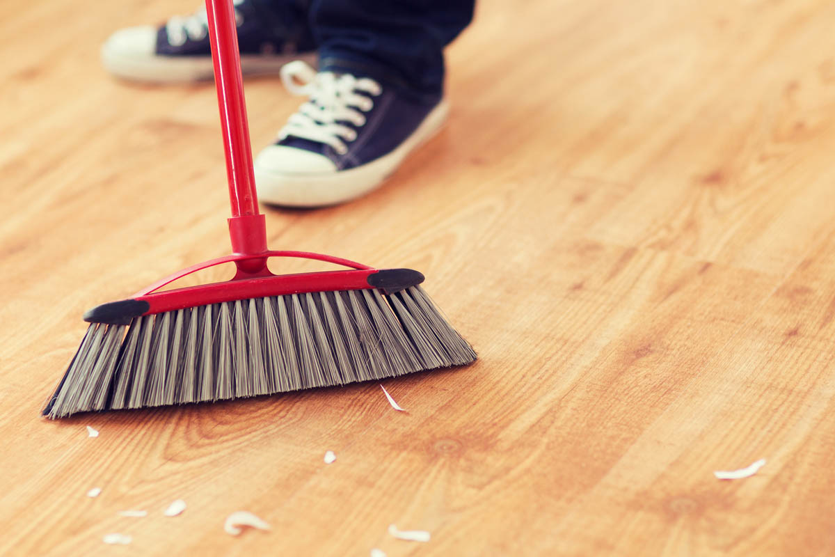 close up of male brooming wooden floor