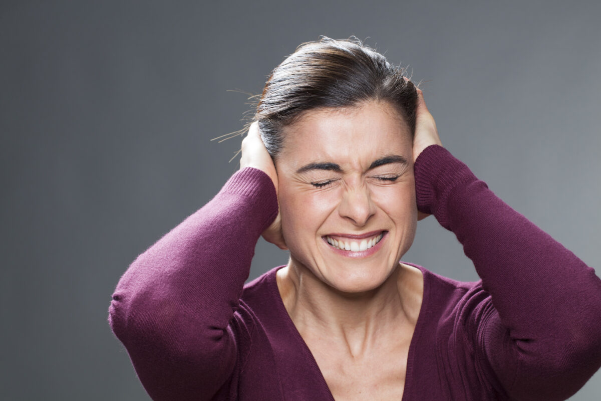 beautiful 30&#8217;s girl suffering from migraine covering ears with hands